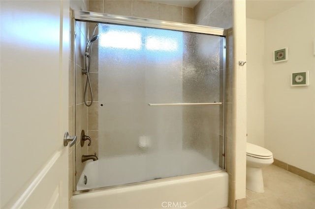 bathroom featuring toilet, shower / bath combination with glass door, and tile patterned flooring