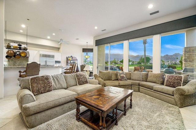 tiled living room with a mountain view and ceiling fan