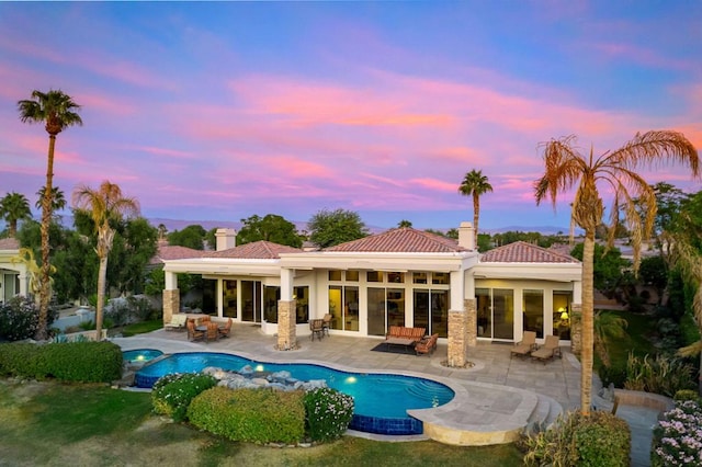 pool at dusk with an outdoor hangout area and a patio