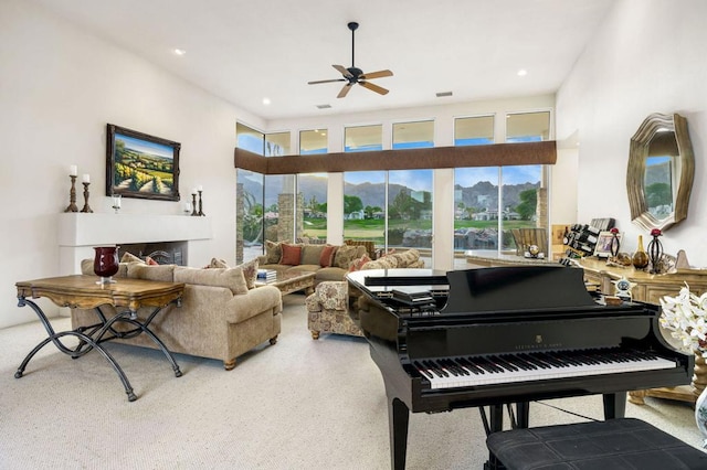 carpeted living room with plenty of natural light, ceiling fan, and a high ceiling