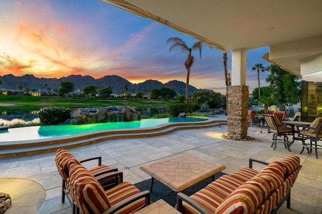 patio terrace at dusk with a water and mountain view and an outdoor hangout area