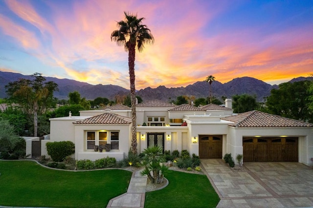 mediterranean / spanish-style home featuring a mountain view, a garage, and a yard