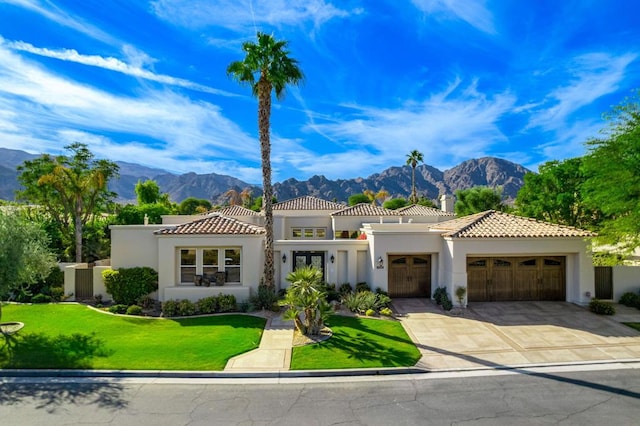 mediterranean / spanish house featuring a mountain view, a garage, and a front lawn