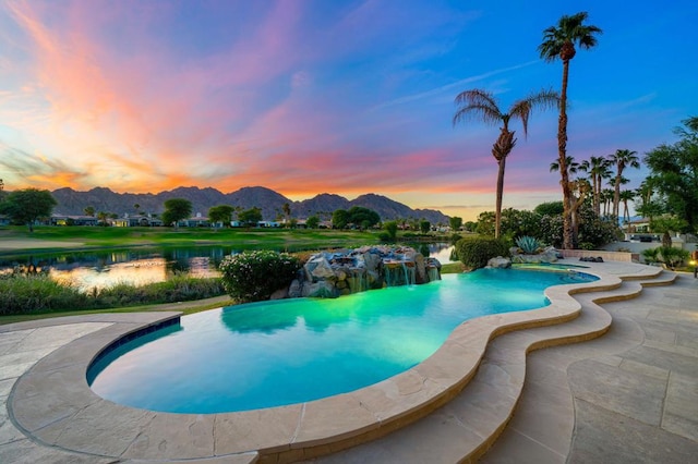 pool at dusk with a water and mountain view