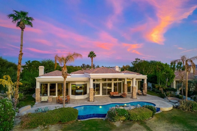 pool at dusk featuring an outdoor living space and a patio