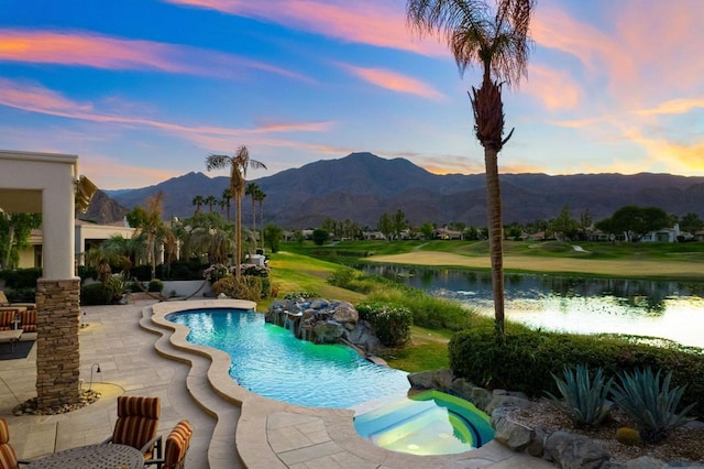 pool at dusk with a patio area, an in ground hot tub, and a water and mountain view