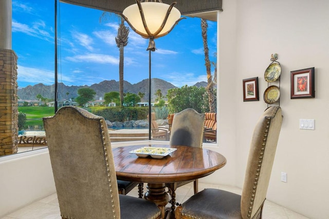 dining room with a mountain view, light tile patterned floors, and a healthy amount of sunlight