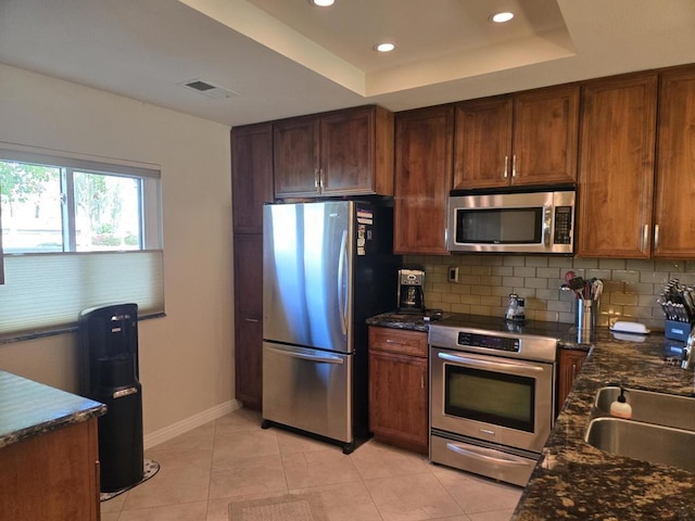 kitchen featuring sink, stainless steel appliances, tasteful backsplash, a raised ceiling, and light tile patterned flooring