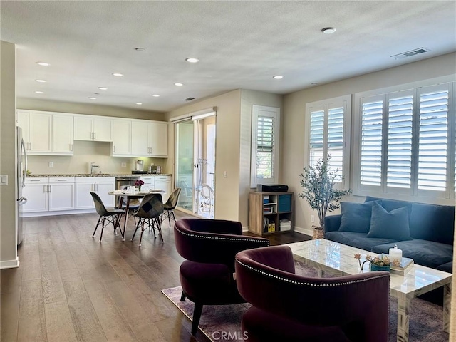 living area with recessed lighting, wood finished floors, visible vents, and baseboards