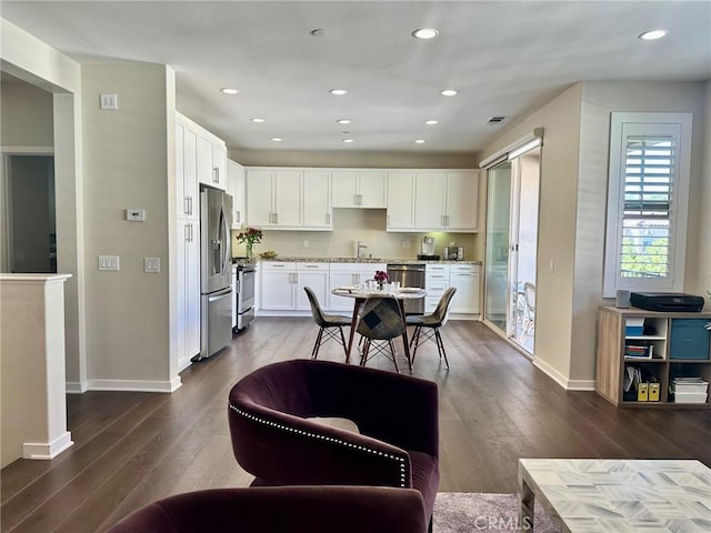 kitchen featuring white cabinetry, stainless steel appliances, baseboards, and dark wood-style flooring