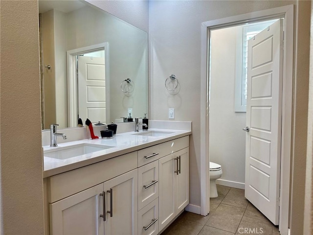 bathroom with tile patterned floors, toilet, double vanity, and a sink