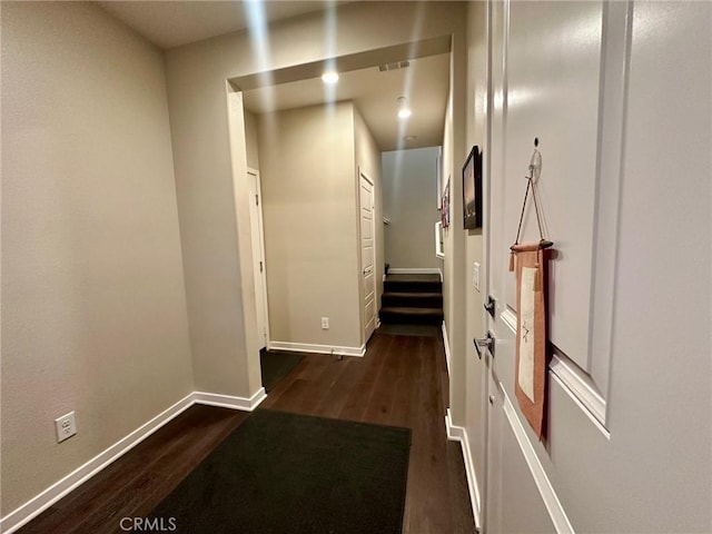 hall featuring baseboards and dark wood-style flooring