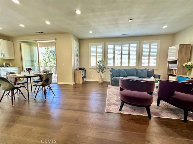 living area featuring a wealth of natural light, visible vents, dark wood finished floors, and baseboards