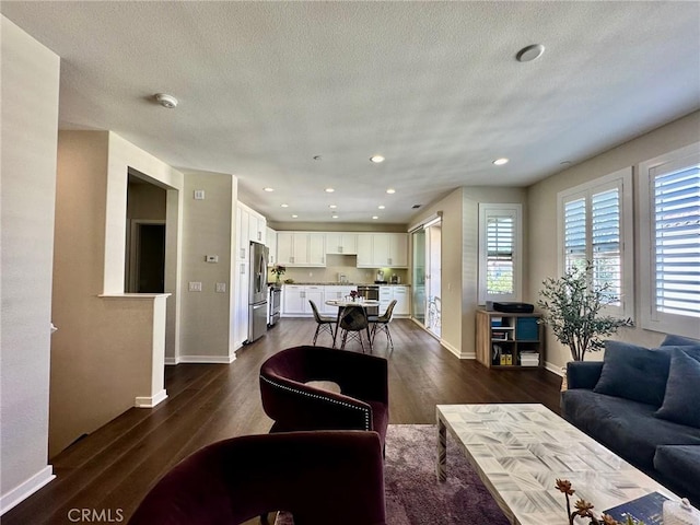 living room featuring dark wood-type flooring, baseboards, and a textured ceiling