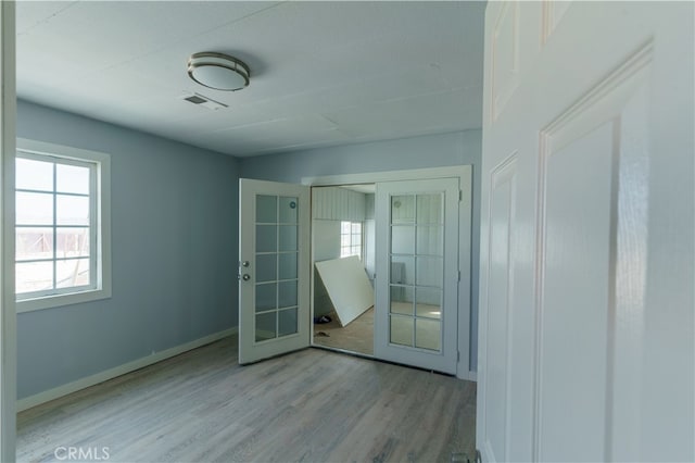 spare room featuring french doors and light wood-type flooring