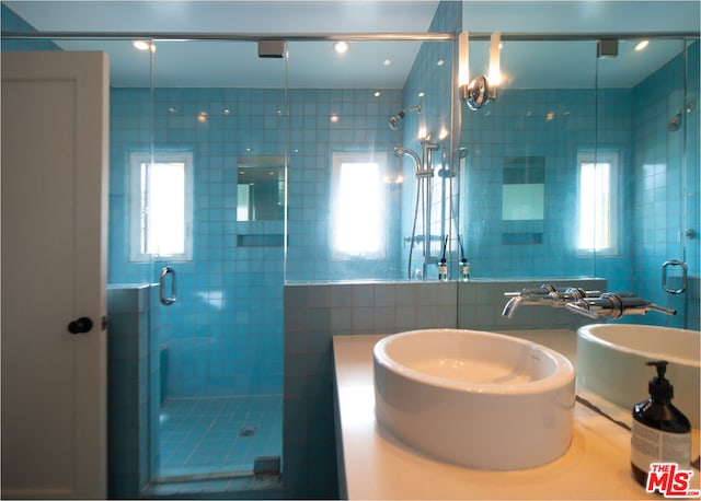 bathroom featuring a shower with door, tile walls, and sink