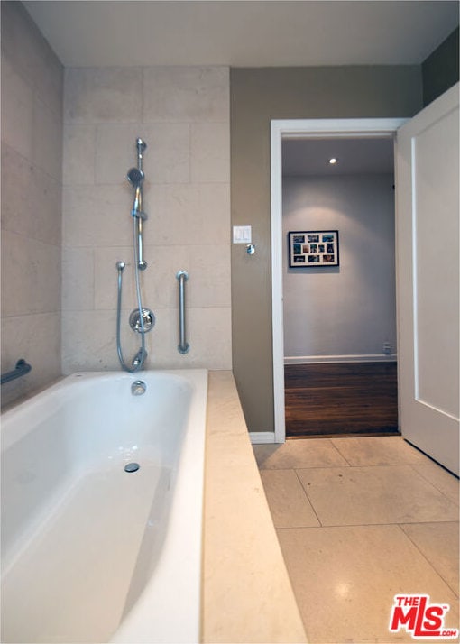 bathroom with tile patterned floors and a bath