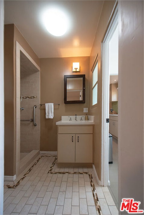 bathroom with tile patterned flooring, vanity, and tiled shower