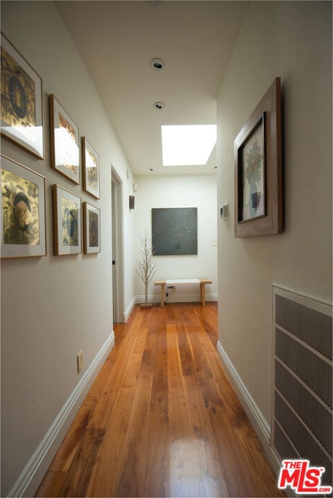 hallway featuring a skylight and wood-type flooring