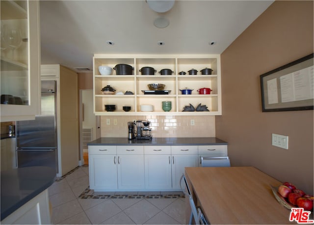 kitchen with tasteful backsplash, high quality fridge, white cabinetry, and light tile patterned flooring