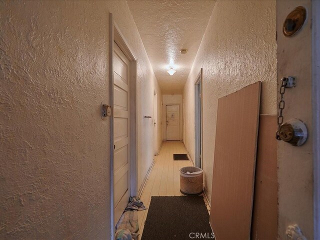 hallway with light hardwood / wood-style floors and a textured ceiling