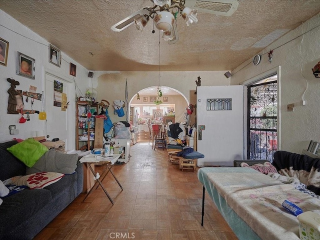 living room with ceiling fan and a textured ceiling