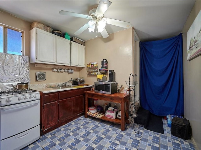 kitchen with white gas range oven, ceiling fan, and sink