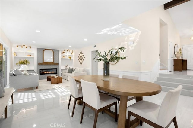 dining space featuring a large fireplace, built in features, light tile patterned floors, and vaulted ceiling