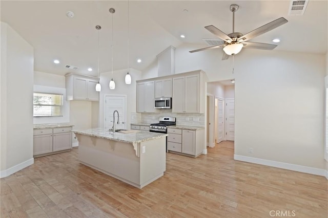 kitchen featuring a center island with sink, white cabinets, light wood-type flooring, and stainless steel appliances