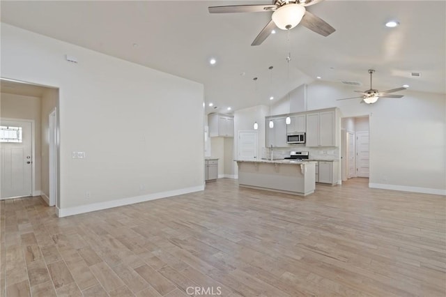 unfurnished living room featuring light hardwood / wood-style flooring, vaulted ceiling, ceiling fan, and sink