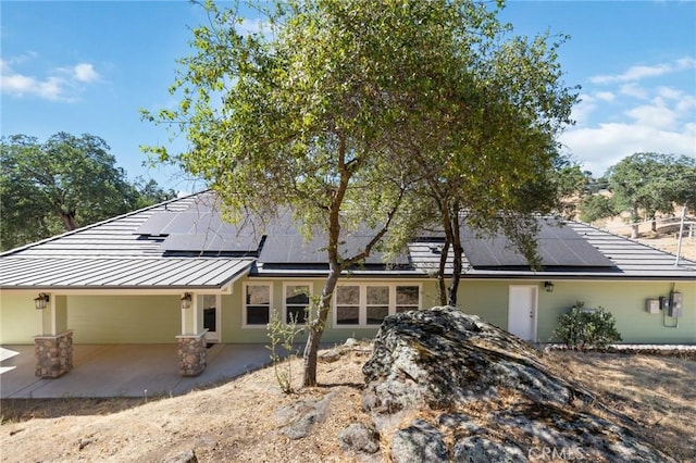 view of home's exterior featuring solar panels and a patio