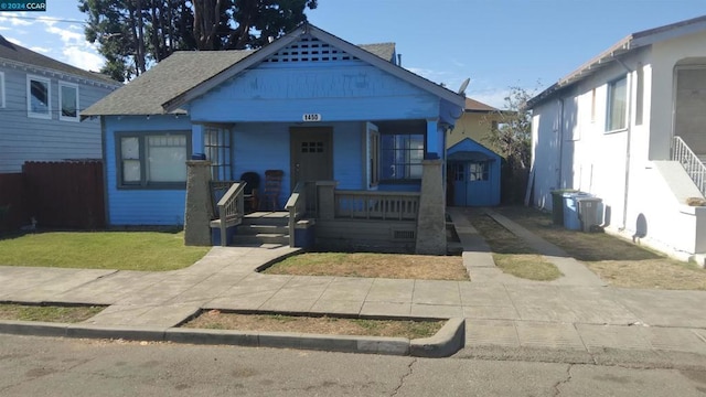 bungalow featuring covered porch and a shed