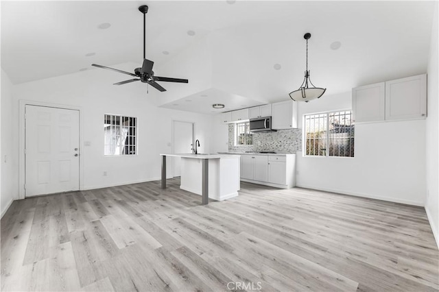 unfurnished living room with light hardwood / wood-style floors, vaulted ceiling, and ceiling fan