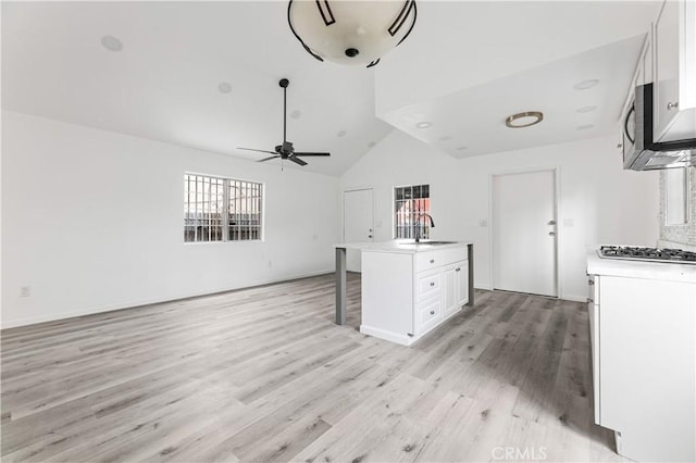 kitchen with ceiling fan, a center island with sink, white cabinets, and sink