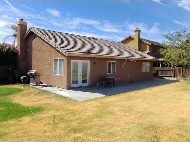 back of property featuring french doors, a patio area, and a lawn