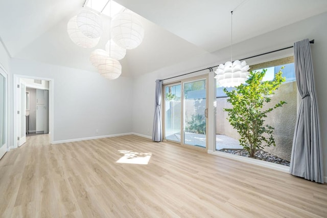 interior space with light hardwood / wood-style floors, an inviting chandelier, and vaulted ceiling