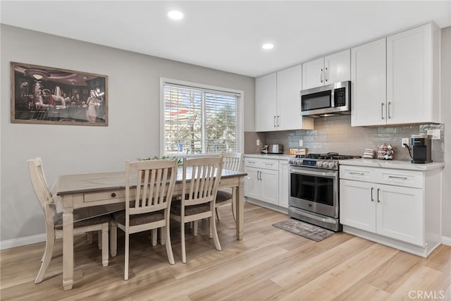 kitchen featuring appliances with stainless steel finishes, decorative backsplash, white cabinetry, and light wood-type flooring