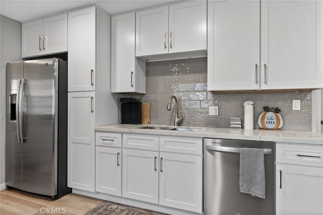 191 Los Angeles Ave, Sugarloaf, CA 92386 - kitchen featuring appliances with stainless steel finishes, white cabinetry, light wood finished floors, a sink, and decorative backsplash