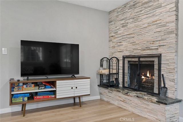 living room featuring a stone fireplace and light hardwood / wood-style floors