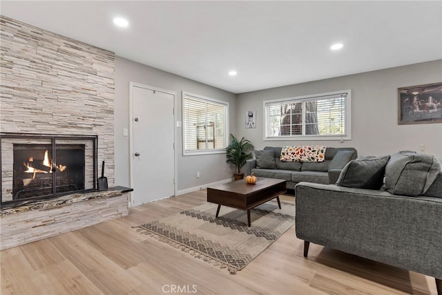 living room featuring a stone fireplace and light hardwood / wood-style flooring