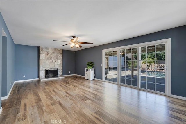 unfurnished living room with a stone fireplace, ceiling fan, and hardwood / wood-style floors