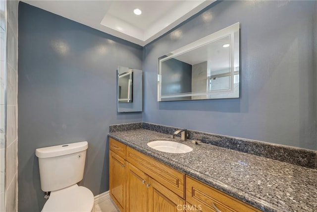 bathroom featuring vanity, toilet, and a tray ceiling