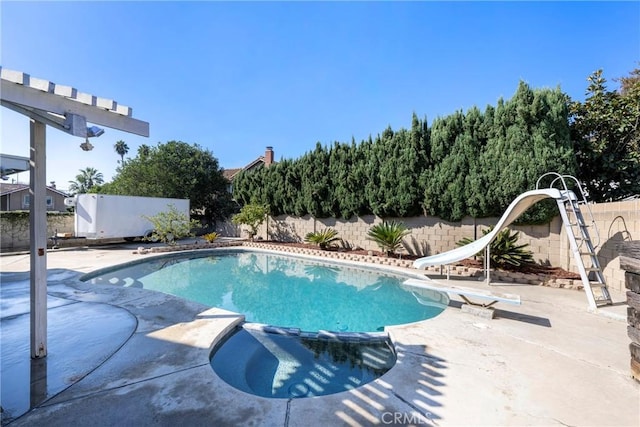 view of swimming pool featuring a patio, an in ground hot tub, and a water slide