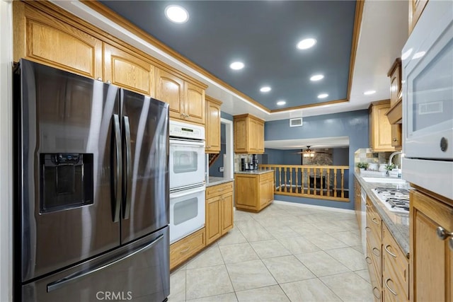 kitchen featuring a tray ceiling, ceiling fan, light tile patterned floors, and appliances with stainless steel finishes