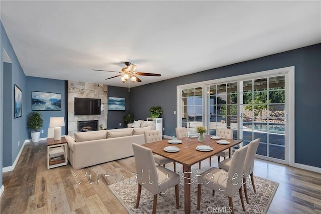 dining room featuring a fireplace, hardwood / wood-style floors, and ceiling fan