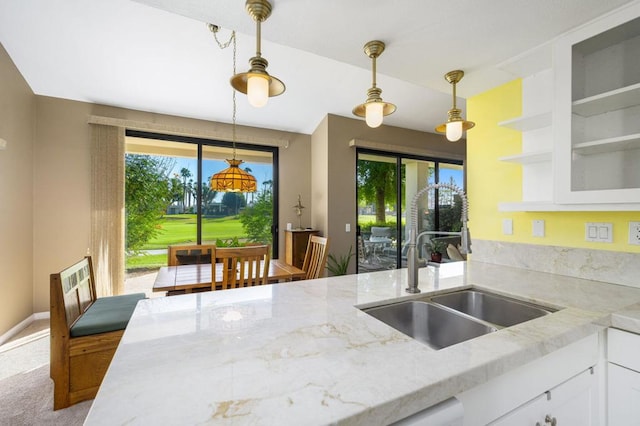 kitchen with light stone countertops, sink, white cabinetry, and plenty of natural light