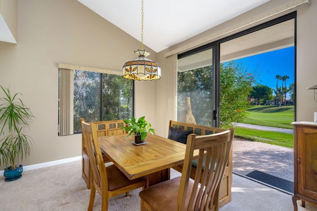 carpeted dining space featuring vaulted ceiling