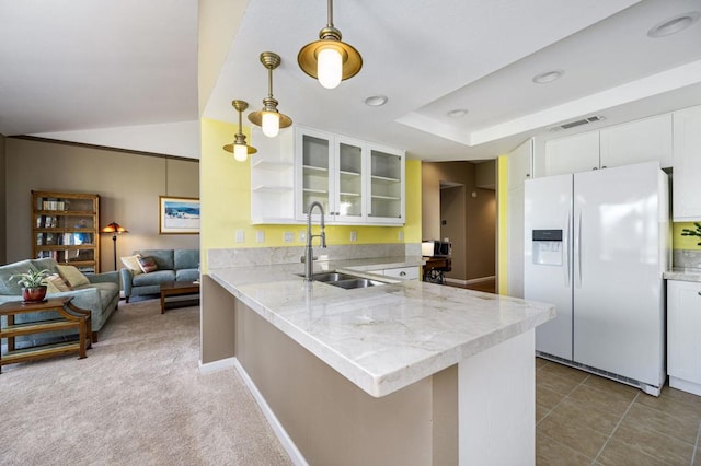 kitchen featuring kitchen peninsula, white cabinets, white fridge with ice dispenser, pendant lighting, and sink