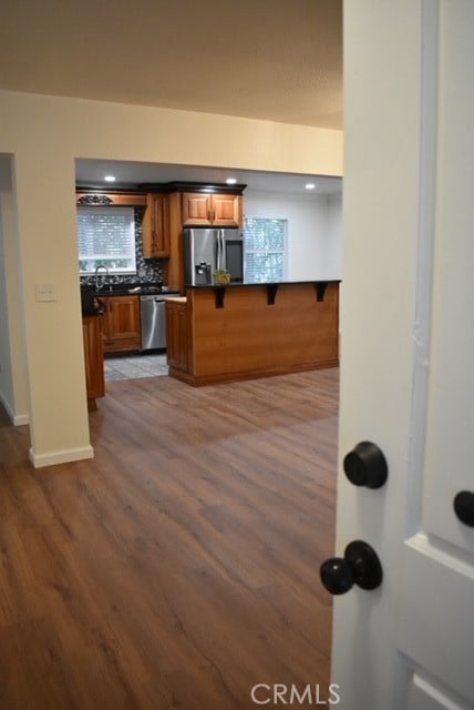 kitchen featuring appliances with stainless steel finishes, kitchen peninsula, hardwood / wood-style floors, and a kitchen bar