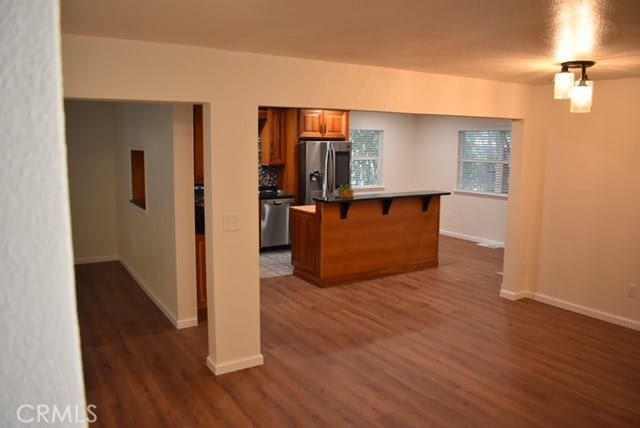 kitchen featuring a kitchen breakfast bar, appliances with stainless steel finishes, a kitchen island, and dark hardwood / wood-style flooring